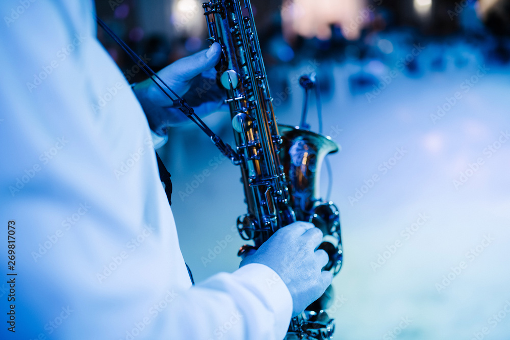 Fototapeta premium The musician plays the saxophone indoors close-up. The saxophonist plays the saxophone at the event close-up.