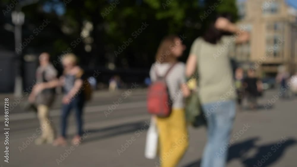 Blurred crowd of people are walking along the sidewalk near the road. Blurred crowd of people are walking along the sidewalk near the road.