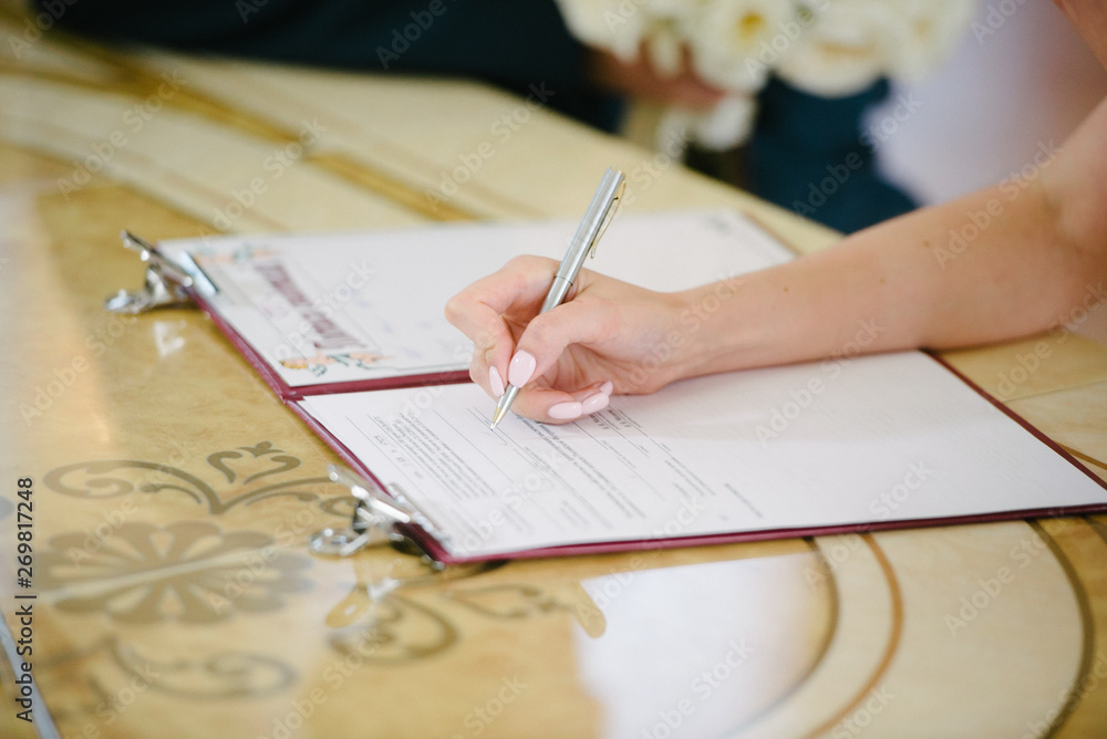 The bride signs on the registration in the document on the wedding day The bride signs on the registration in the document on the wedding day