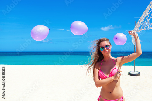Travel vacation  - Beautiful young pretty blonde girl in bikini with white sand on her perfect sport sexy body relax in sea of white sand paradise tropical at sunny day with balloons celebration