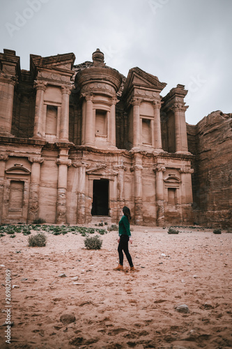 Woman standing in front of ancient temple in rock face in Al Khazneh, Petra, Jordan