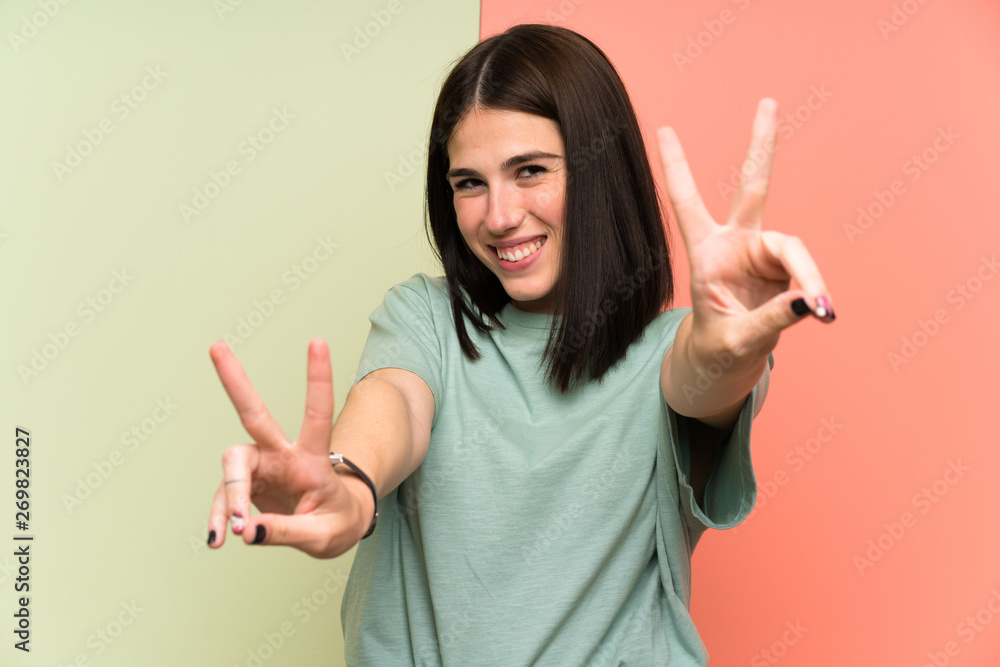 Young woman over isolated colorful wall smiling and showing victory sign Young woman over isolated colorful wall smiling and showing victory sign