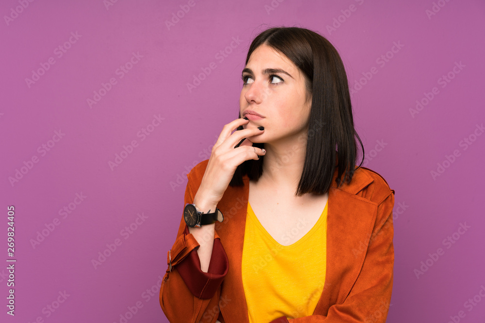 Young woman with a coat over isolated purple background standing and thinking an idea Young woman with a coat over isolated purple background standing and thinking an idea