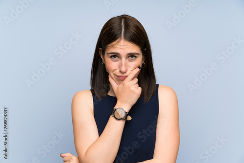 Young woman over isolated blue wall standing and thinking an idea