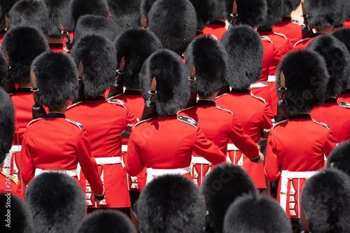 Close up of soldiers marching at the Trooping the Colour military parade at Horse Guards, London UK. Guards are wearing iconic black and red uniform and bearskin hats. photo