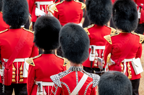 Close up of soldiers marching at the Trooping the Colour military parade at Horse Guards, London UK. Guards are wearing iconic black and red uniform and bearskin hats.