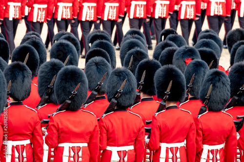 Close up of soldiers marching at the Trooping the Colour military parade at Horse Guards, London UK. Guards are wearing iconic black and red uniform and bearskin hats. photo