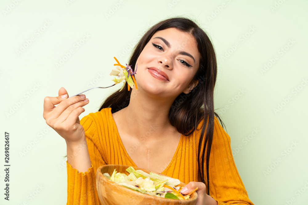 Happy Teenager girl with salad over green wall Happy Teenager girl with salad over green wall