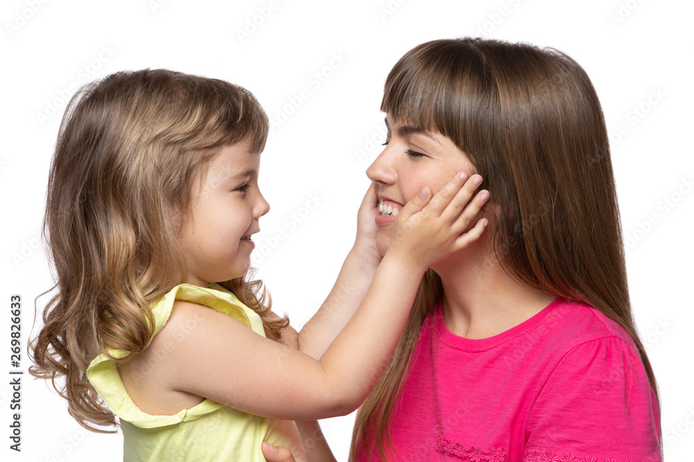 happy mom and her little daughter facing each other, a girl stretches her hands to mom, emotions, on a white background happy mom and her little daughter facing each other, a girl stretches her hands to mom, emotions, on a white background