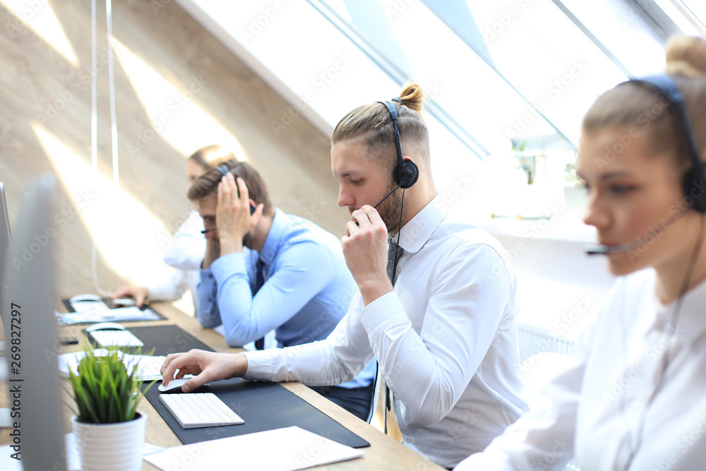 Fototapeta premium Portrait of call center worker accompanied by his team. Smiling customer support operator at work.