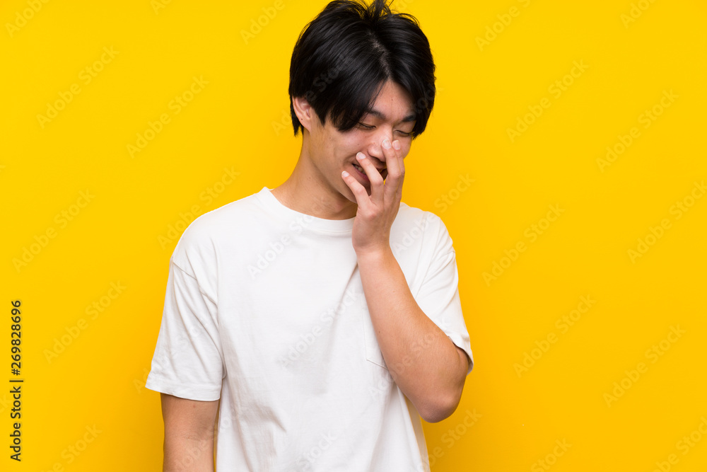 Asian man over isolated yellow wall smiling a lot Asian man over isolated yellow wall smiling a lot
