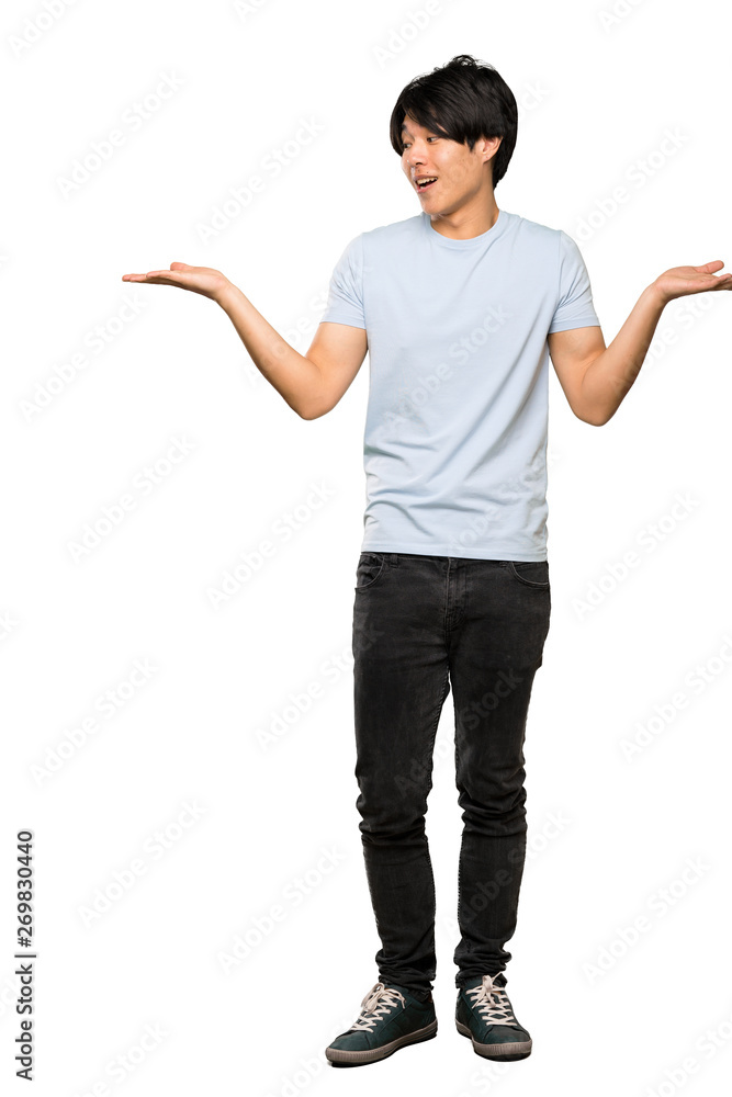 A full-length shot of a Asian man with blue shirt holding copyspace with two hands over isolated white background A full-length shot of a Asian man with blue shirt holding copyspace with two hands over isolated white background