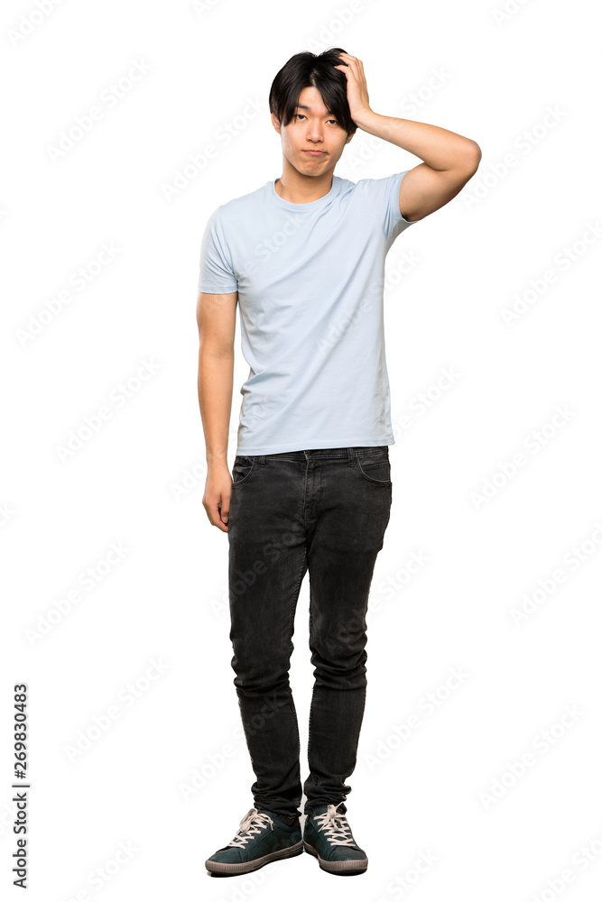 A full-length shot of a Asian man with blue shirt with an expression of frustration and not understanding over isolated white background A full-length shot of a Asian man with blue shirt with an expression of frustration and not understanding over isolated white background