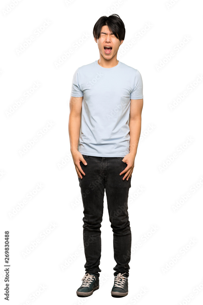 A full-length shot of a Asian man with blue shirt shouting to the front with mouth wide open over isolated white background A full-length shot of a Asian man with blue shirt shouting to the front with mouth wide open over isolated white background