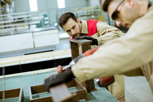 Two young workers assembling furniture in the factory