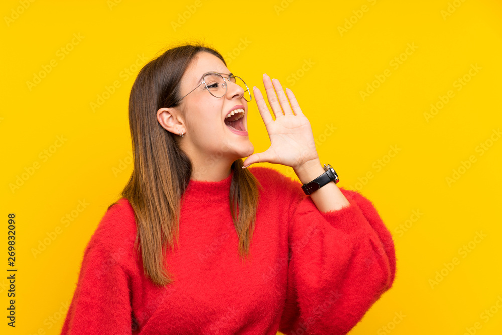 Young woman over isolated yellow wall shouting with mouth wide open Young woman over isolated yellow wall shouting with mouth wide open