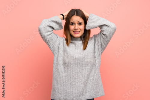 Young woman over pink wall frustrated and takes hands on head © luismolinero