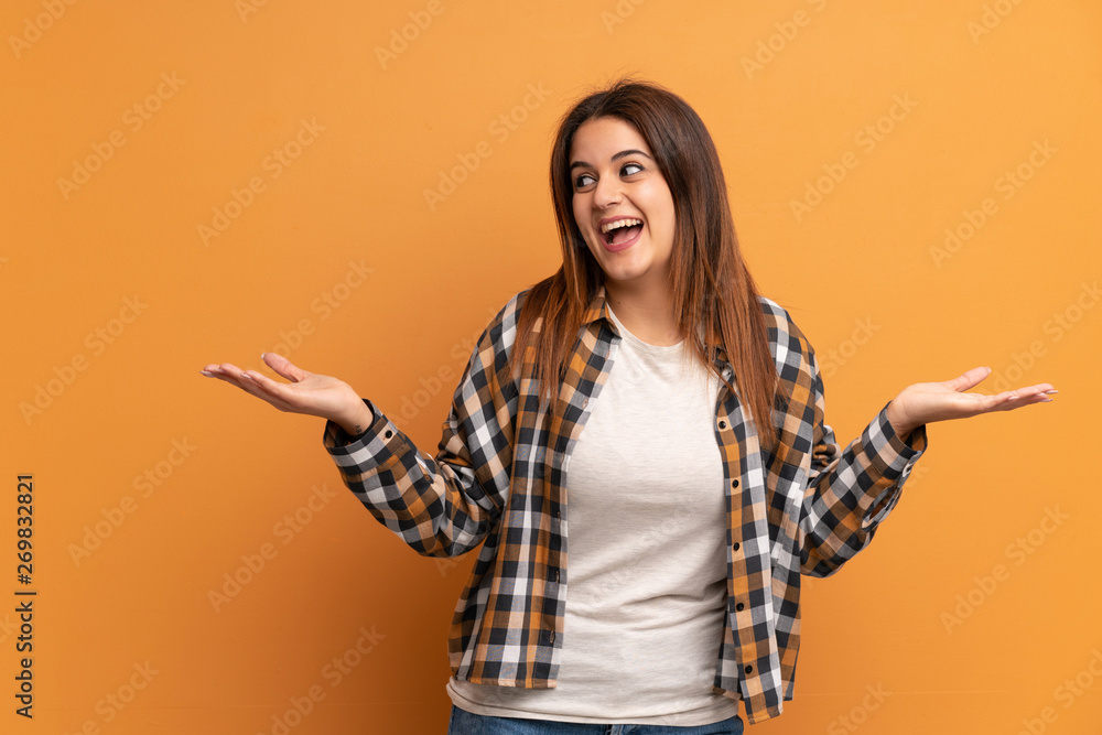 Young woman over brown wall holding copyspace with two hands Young woman over brown wall holding copyspace with two hands