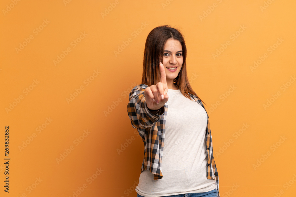 Young woman over brown wall showing and lifting a finger Young woman over brown wall showing and lifting a finger