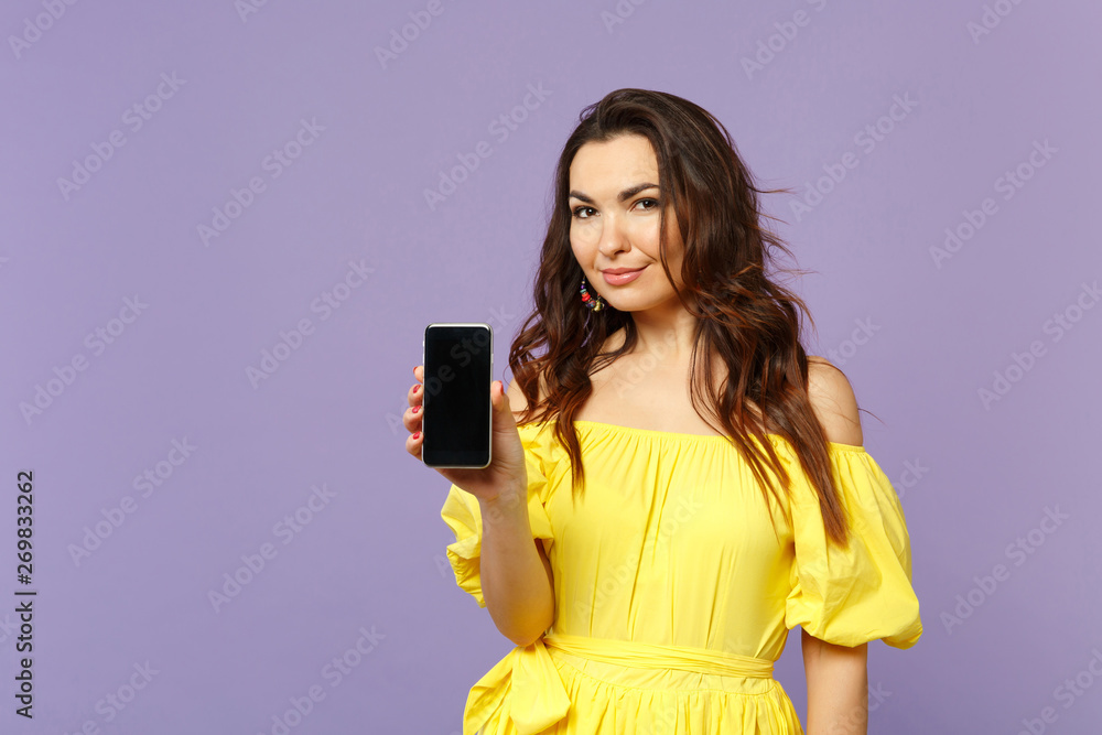 Beautiful young woman in yellow summer dress holding mobile phone with blank empty screen isolated on pastel violet background in studio. People sincere emotions lifestyle concept. Mock up copy space. Beautiful young woman in yellow summer dress holding mobile phone with blank empty screen isolated on pastel violet background in studio. People sincere emotions lifestyle concept. Mock up copy space.