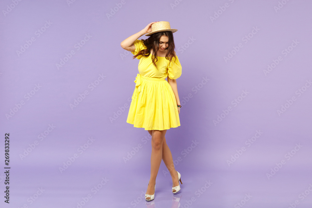 Charming young woman in yellow dress summer hat looking down, putting hand on head isolated on pastel violet wall background in studio. People sincere emotions, lifestyle concept. Mock up copy space. Charming young woman in yellow dress summer hat looking down, putting hand on head isolated on pastel violet wall background in studio. People sincere emotions, lifestyle concept. Mock up copy space.