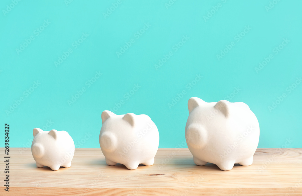 Growing money and financial concepts with 3 size of piggy on wood table background.savings and investment Growing money and financial concepts with 3 size of piggy on wood table background.savings and investment