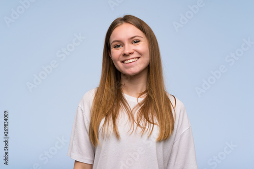 Young woman over blue wall smiling