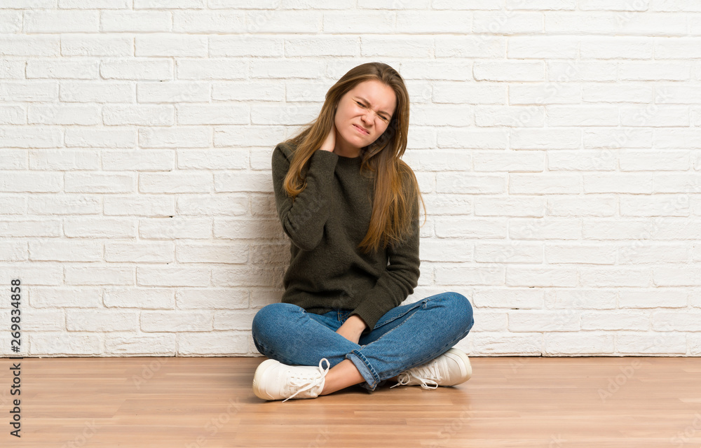 Young woman sitting on the floor with neckache Young woman sitting on the floor with neckache