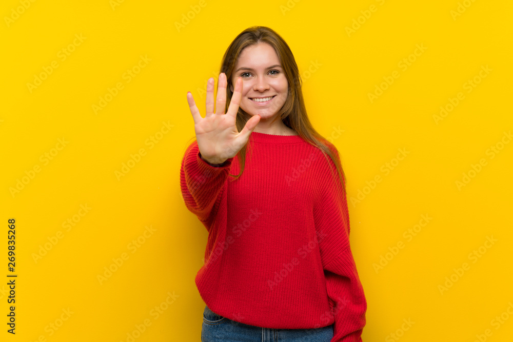 Young woman over yellow wall counting five with fingers Young woman over yellow wall counting five with fingers