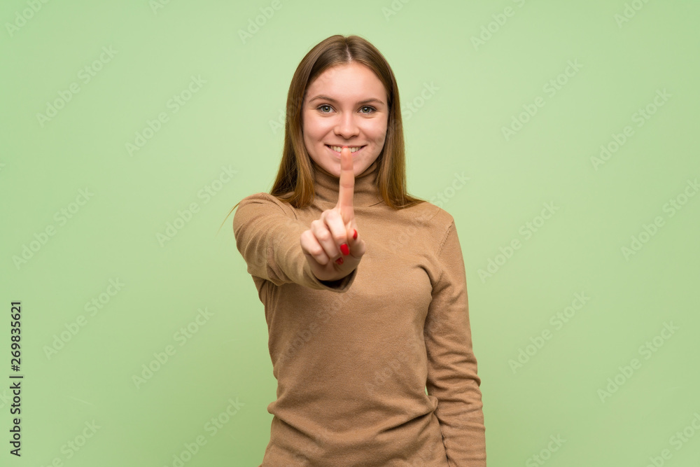 Young woman with turtleneck sweater showing and lifting a finger Young woman with turtleneck sweater showing and lifting a finger