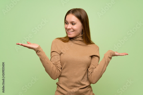 Young woman with turtleneck sweater holding copyspace with two hands