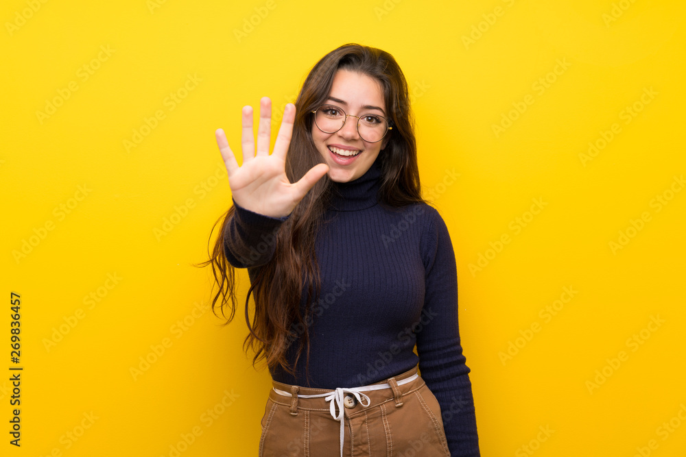 Teenager girl over isolated yellow wall counting five with fingers Teenager girl over isolated yellow wall counting five with fingers