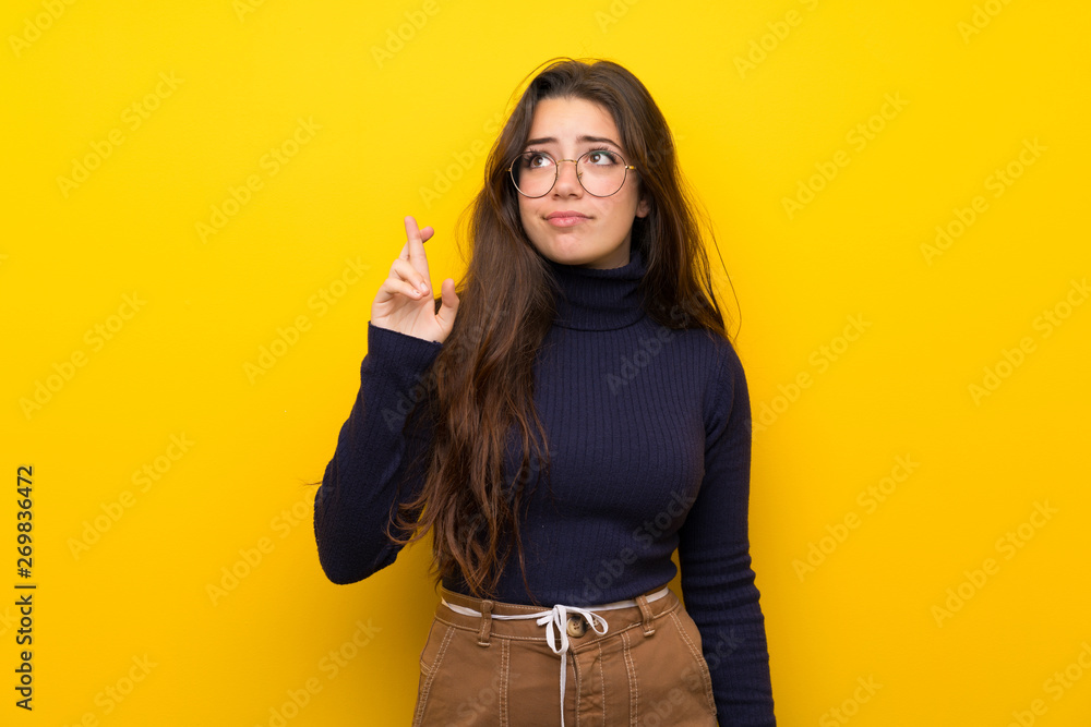 Teenager girl over isolated yellow wall with fingers crossing and wishing the best Teenager girl over isolated yellow wall with fingers crossing and wishing the best