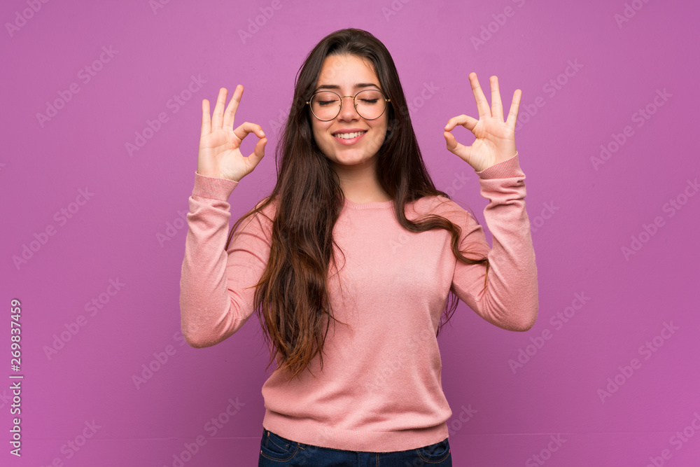 Teenager girl over purple wall in zen pose Teenager girl over purple wall in zen pose