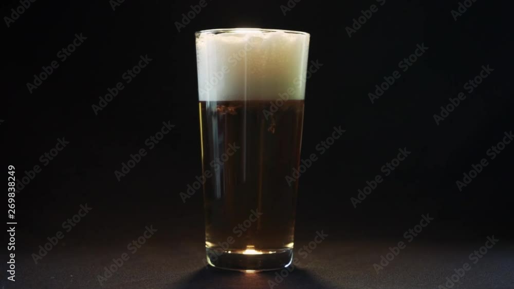 Glass of beer at black background. Slow motion. Beer bubbles slow motion. Close up view. Glass of beer at black background. Slow motion. Beer bubbles slow motion. Close up view.