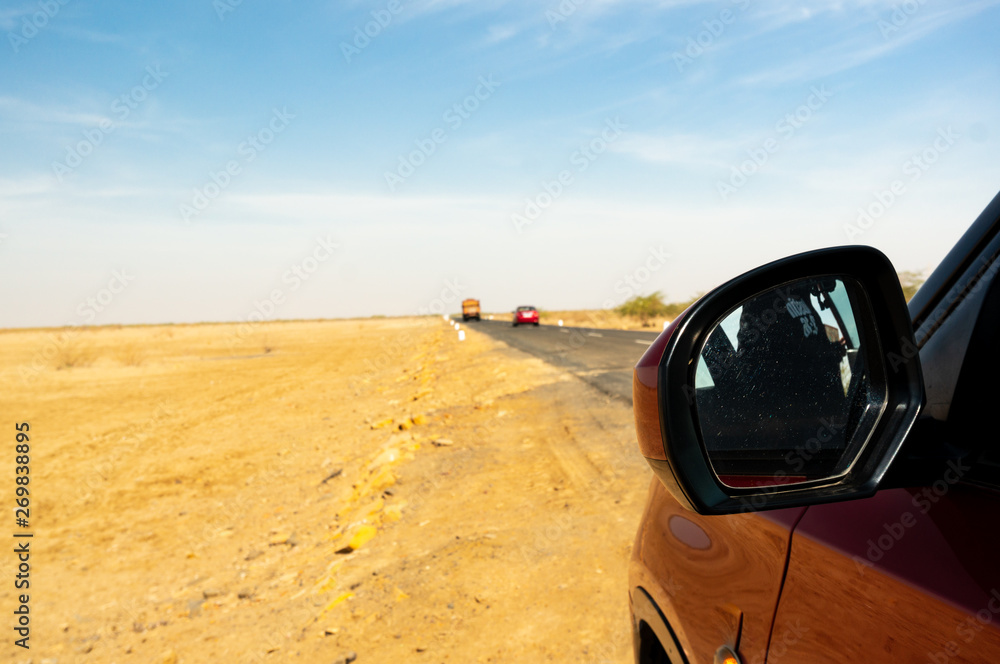 Shot showing red car on a long stretch of empty highway in Rann of Kutch Gujarat