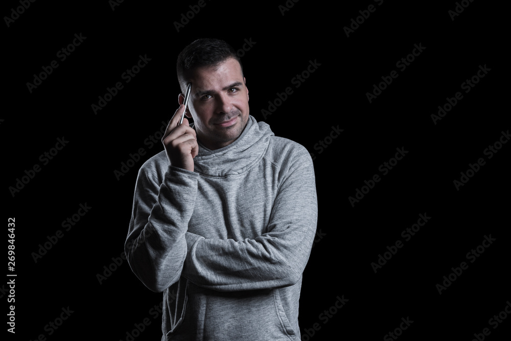 Studio portrait of a man thinking while looking at the camera. Isolated on black background. Horizontal.