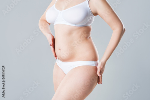 Woman with fat flabby belly, overweight female body on gray background