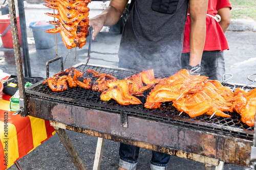 Vendor selling barbeue chicken wings in street market bazaar photo