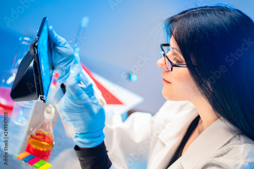 Laboratory cosmetics. A female laboratory assistant studies the results of testing received by e-mail. Formulation development of cosmetics. Creation of cosmetics in the laboratory. Cosmeceuticals. photo