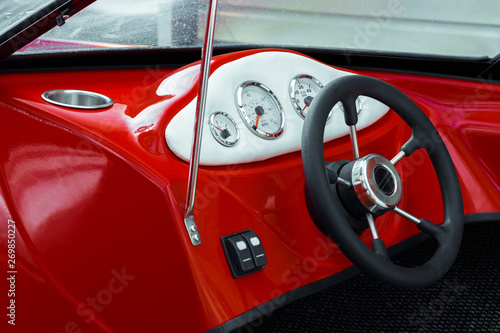 Steering wheel and dashboard of a red sports boat