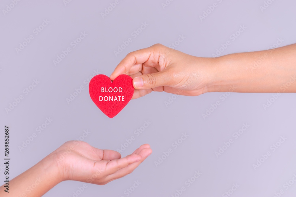 Obraz premium Woman hand gives a red heart to a boy hand for blood donation concept,World blood donor day. Copy space for advertisers.