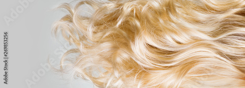 Hair. Beautiful healthy long curly blond hair closeup texture. Dyed wavy blonde hair background. Coloring concept. Haircare