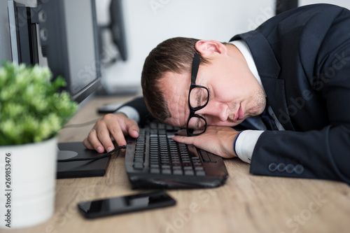 close up portrait of tired businessman sleeping on the table in modern office