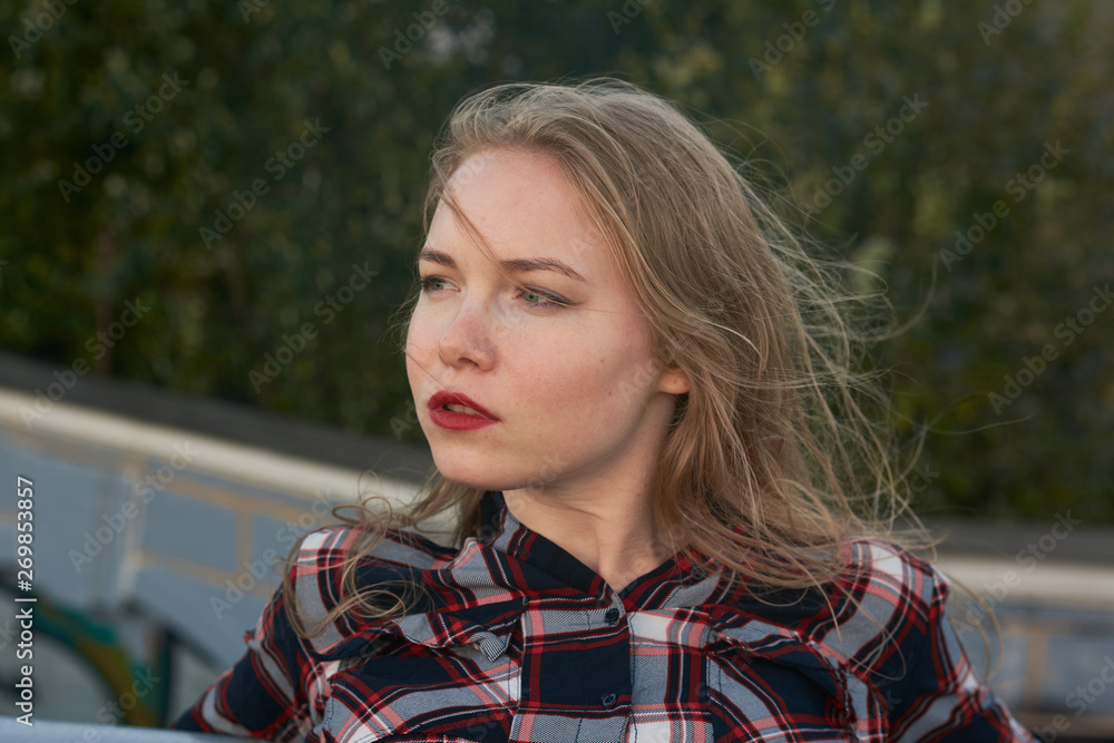 Blonde in a plaid shirt in windy weather on railway tracks. Blonde in a plaid shirt in windy weather on railway tracks.