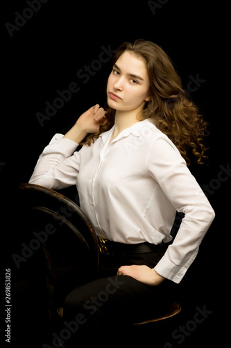 Fashionable girl teenager studio photo on a black background.