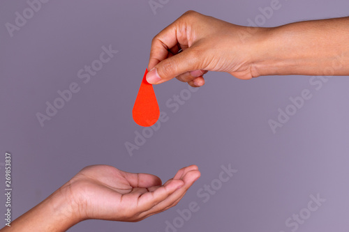 Cuadro en lienzo Woman hand gives a red heart to a boy hand for blood donation concept,World blood donor day