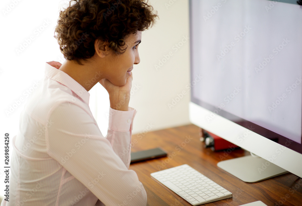 young woman sitting with computer and looking at screen