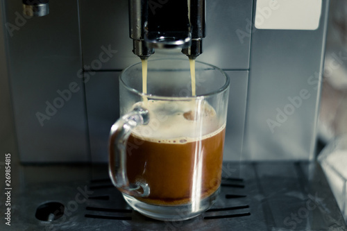Cup in the coffee machine. The process of making coffee. Coffee slowly flows into the cup