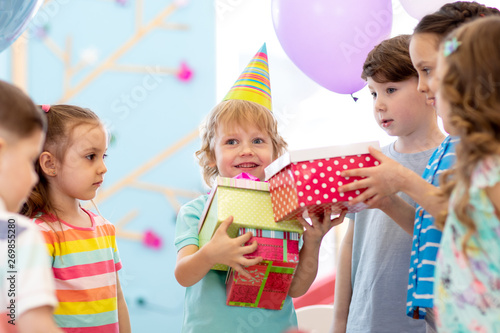 Joyful little child boy receiving gifts at birthday party. Holidays, birthday concept.